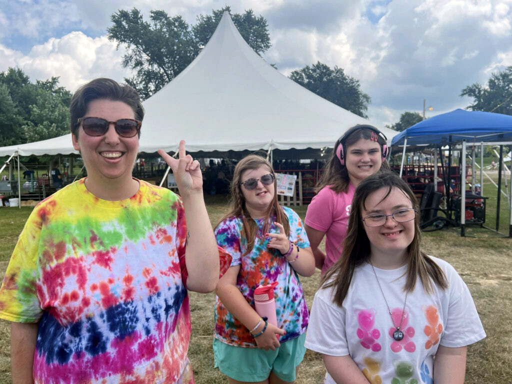 Four Onward Adult Day Center participants posing together in front of some tents outside.