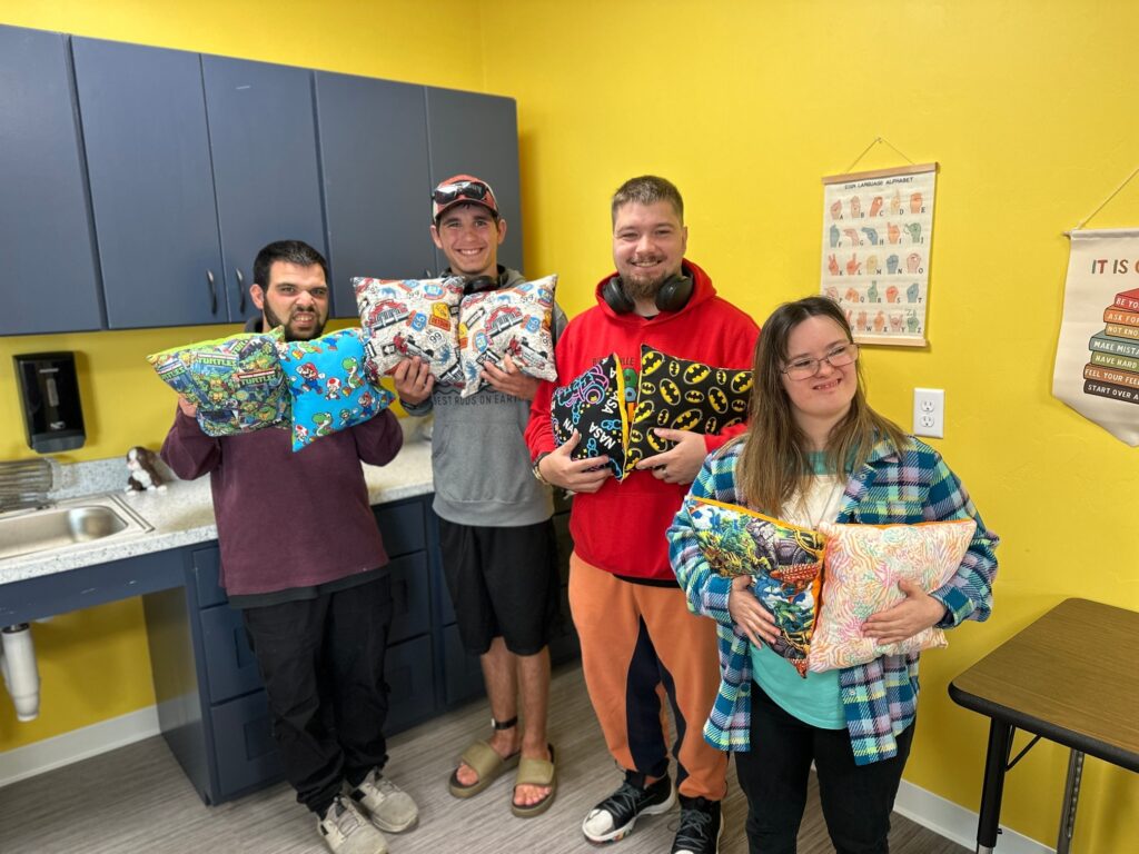Four Onward Adult Day Center participants holding their pillows that they made themselves.